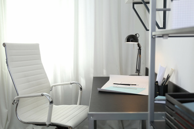 Photo of Stylish room interior with comfortable workplace near window. Design idea