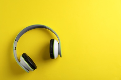 Wireless headphones on color background, top view. Space for text