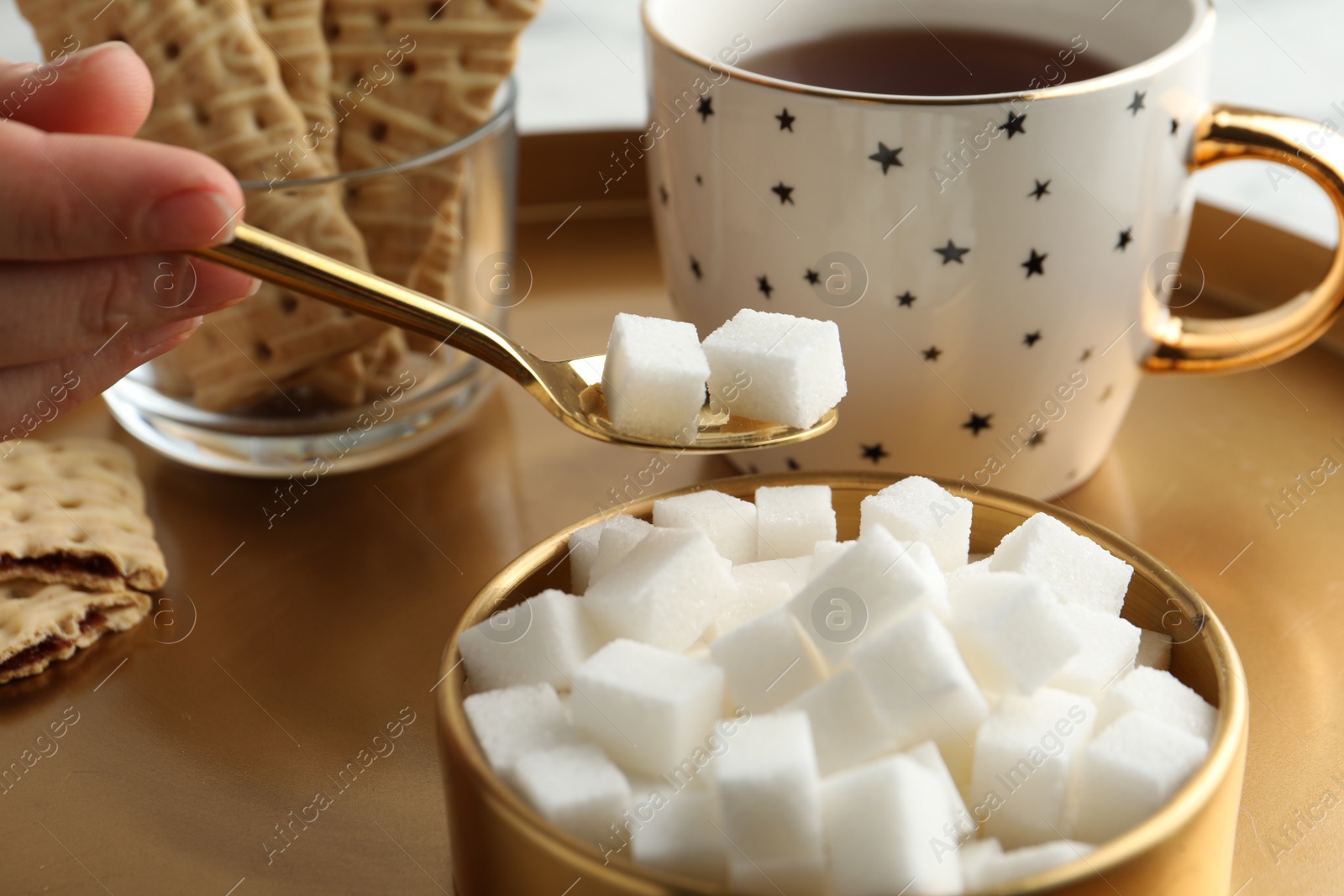 Photo of Woman taking sugar cubes from bowl at table, closeup