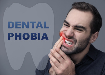 Dental phobia concept. Young man suffering from toothache on grey background