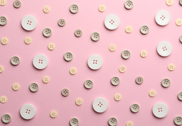 Different sewing buttons on pink background, flat lay