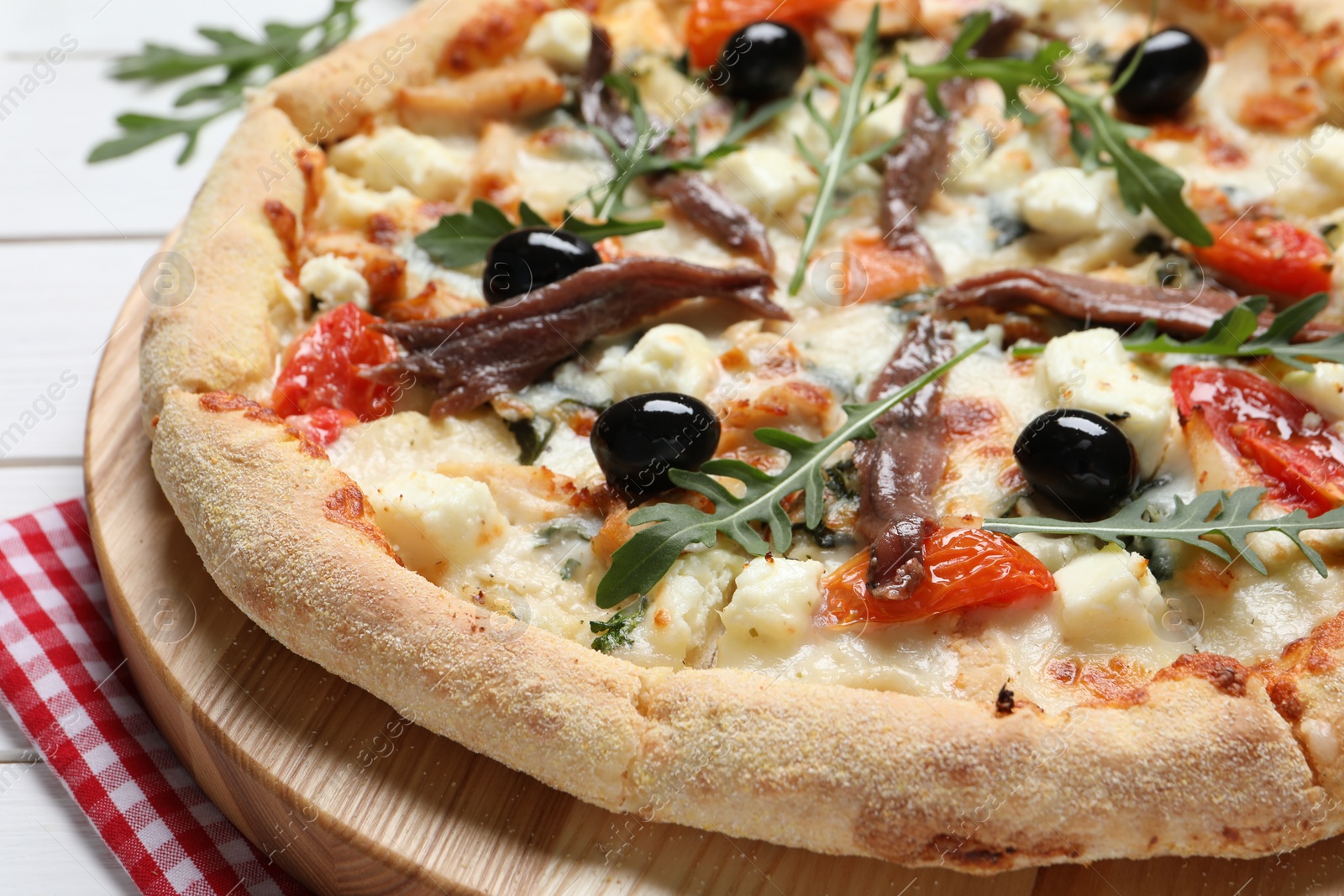 Photo of Tasty pizza with anchovies, arugula and olives on white wooden table, closeup
