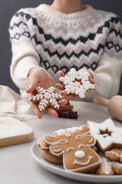 Woman holding delicious homemade Christmas cookies at grey marble table, closeup