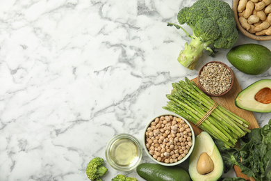 Photo of Different products rich in vitamin E on white marble table, flat lay. Space for text