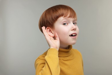 Little boy with hearing problem on grey background