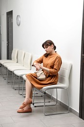 Photo of Woman looking at wrist watch and waiting for appointment indoors