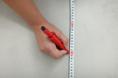 Photo of Worker measuring and marking ceramic tile, closeup