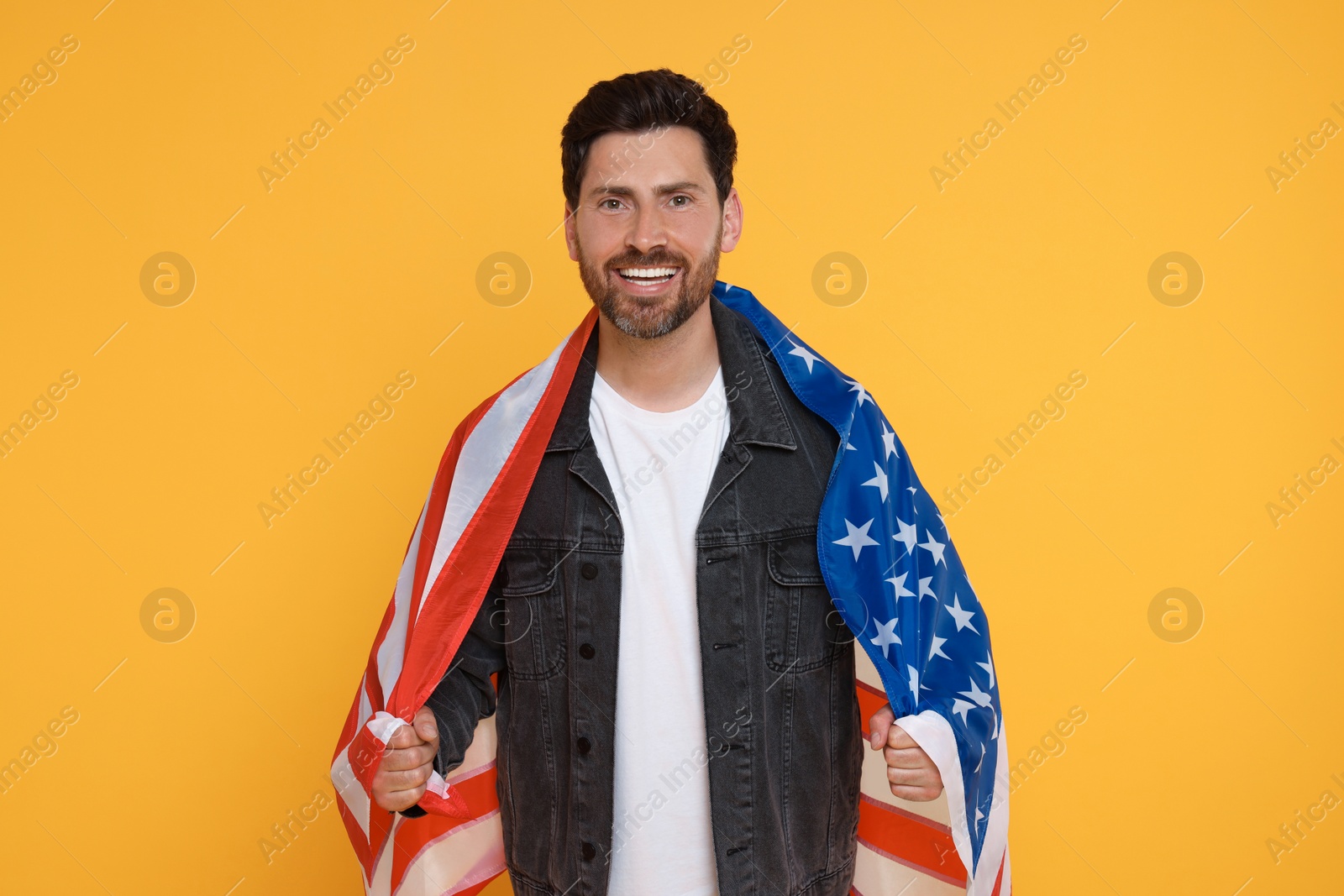 Photo of 4th of July - Independence Day of USA. Happy man with American flag on yellow background