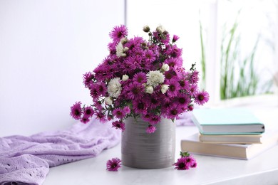Photo of Beautiful flowers, books and violet cloth on white table