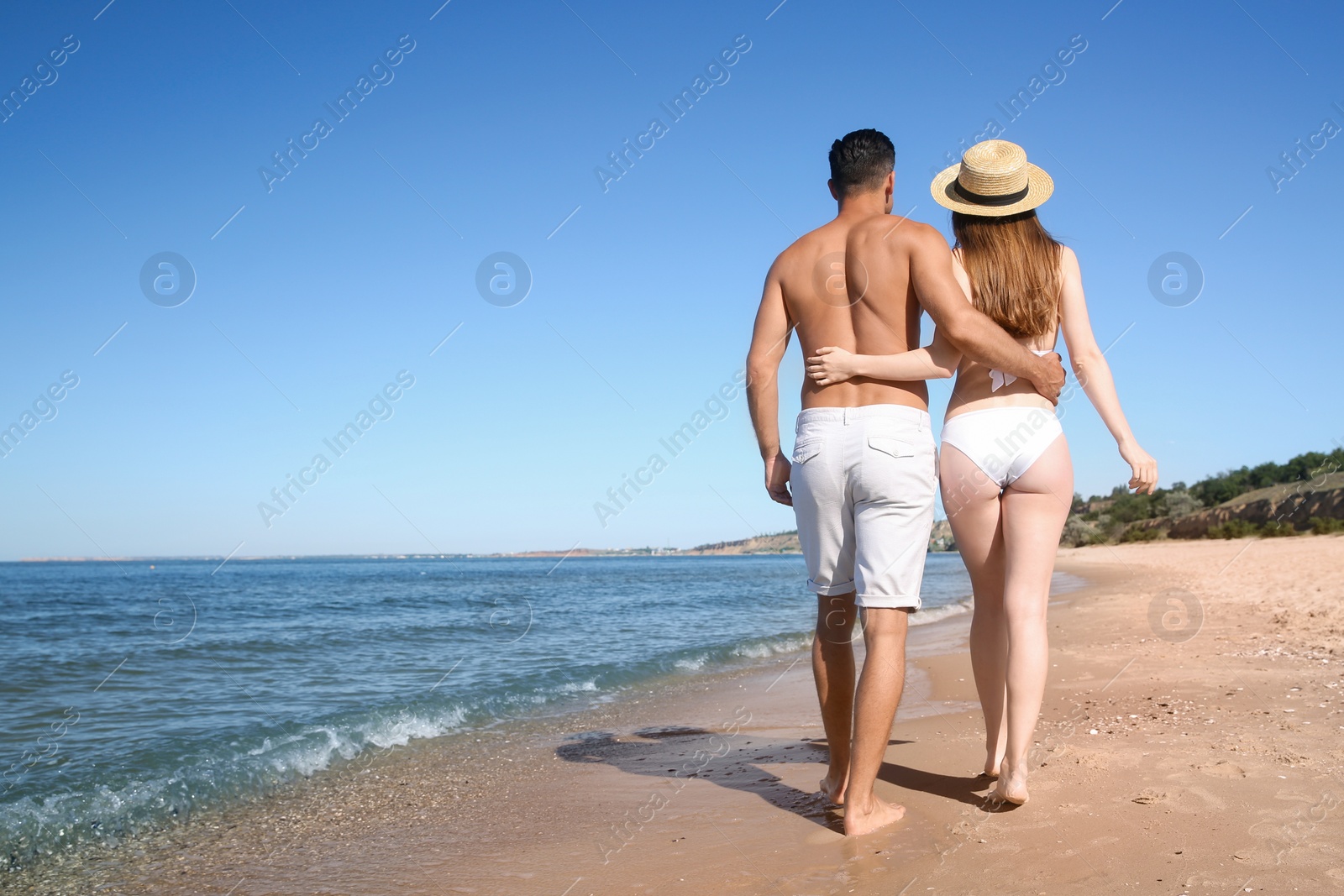 Photo of Woman in bikini and her boyfriend on beach, back view with space for text. Lovely couple