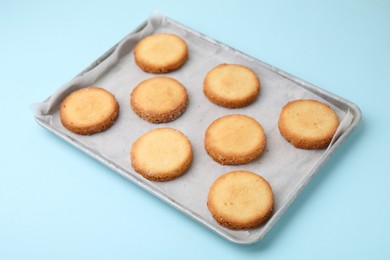 Photo of Tray with tasty sweet sugar cookies on light blue background