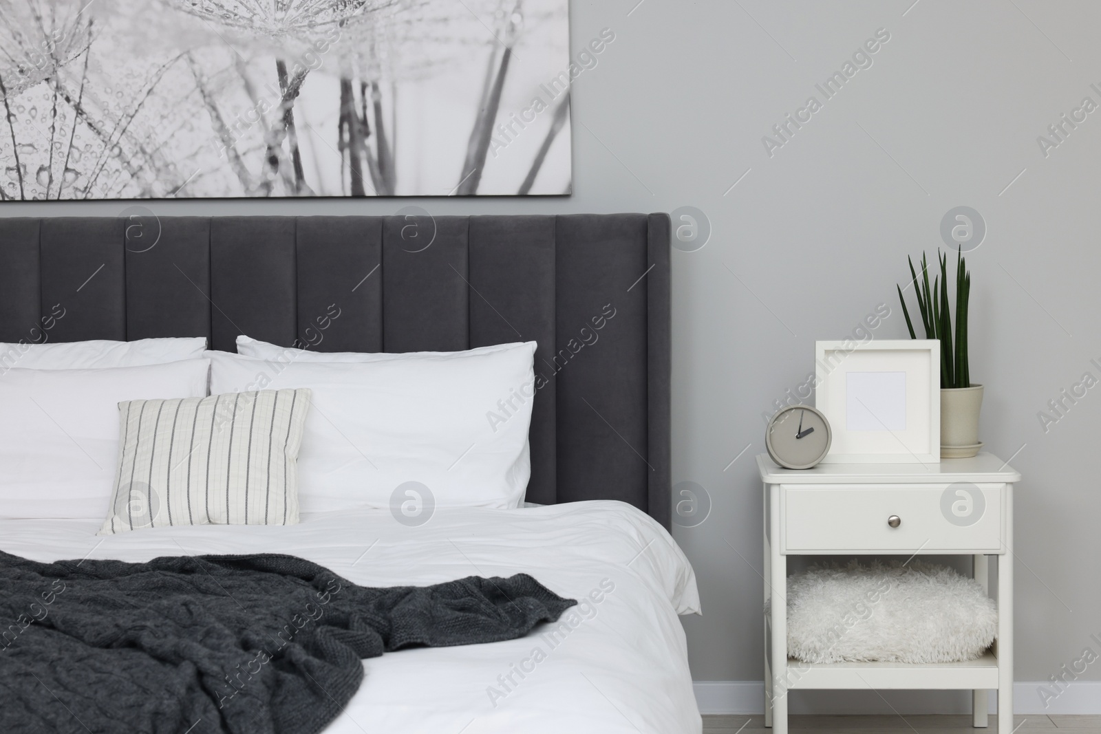 Photo of Large comfortable bed and bedside table in room. Stylish interior