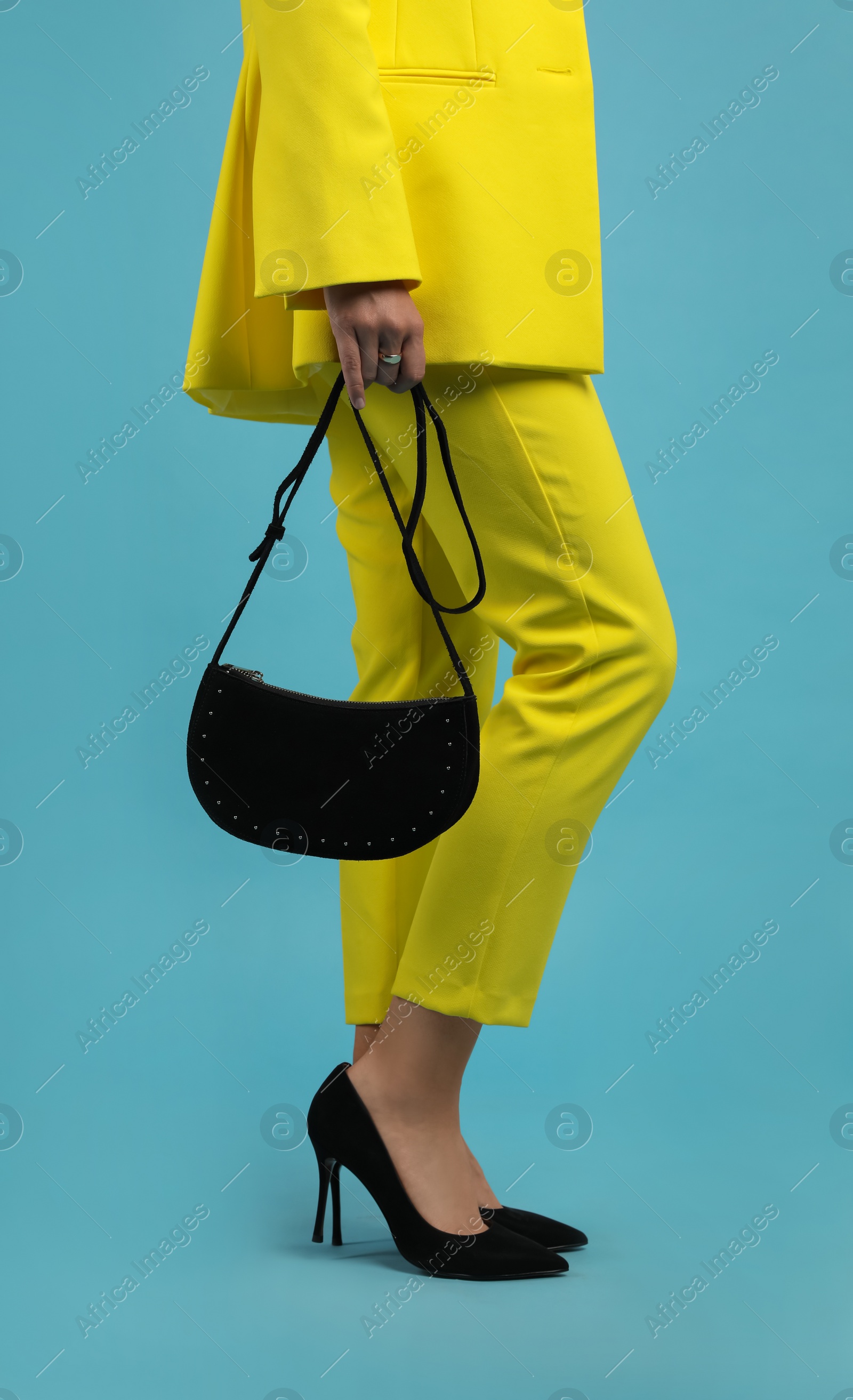 Photo of Fashionable woman with stylish bag on light blue background, closeup