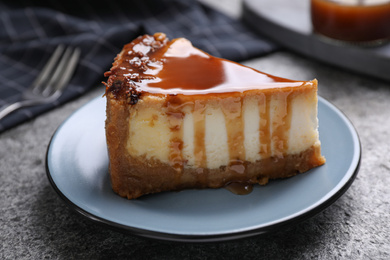 Photo of Piece of delicious cake with caramel served on grey table