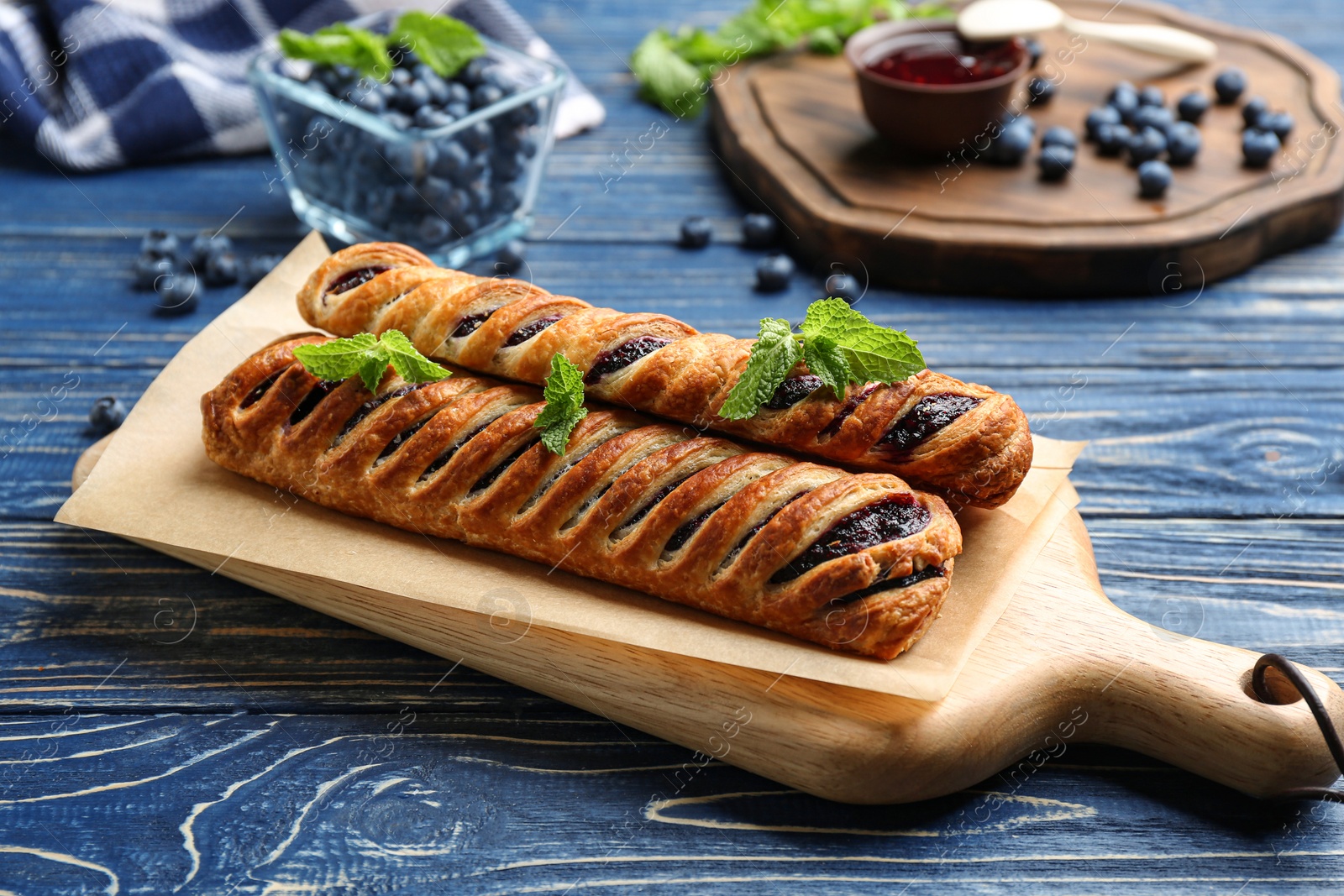 Photo of Fresh delicious puff pastry with sweet berries served on blue wooden table