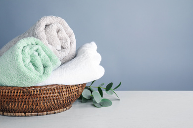 Photo of Fresh towels and eucalyptus branches on light wooden table, space for text