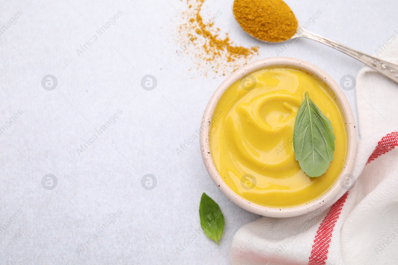 Photo of Tasty curry sauce, powder and basil leaves on light table, flat lay. Space for text