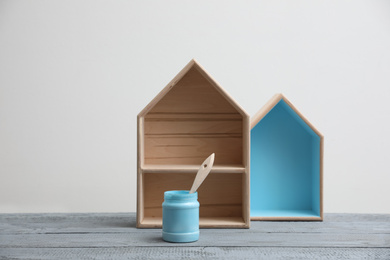 Photo of Brush with paint and wooden houses on grey table