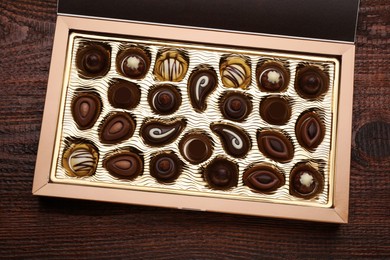 Box of delicious chocolate candies on wooden table, top view