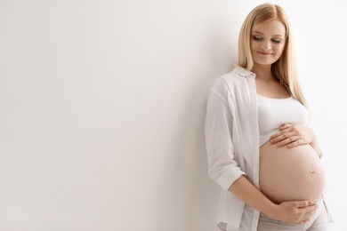 Photo of Portrait of beautiful pregnant woman on light background. Space for text