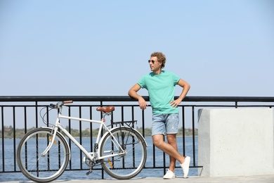 Handsome young man with bicycle outdoors on sunny day