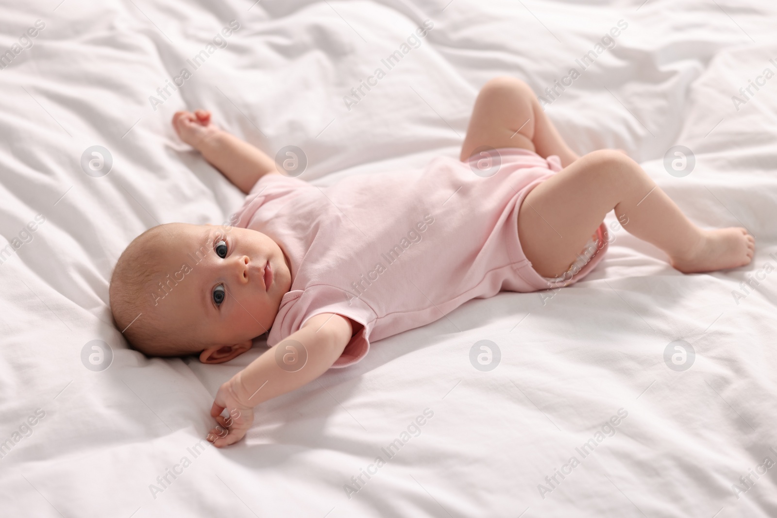 Photo of Cute little baby lying on white sheets