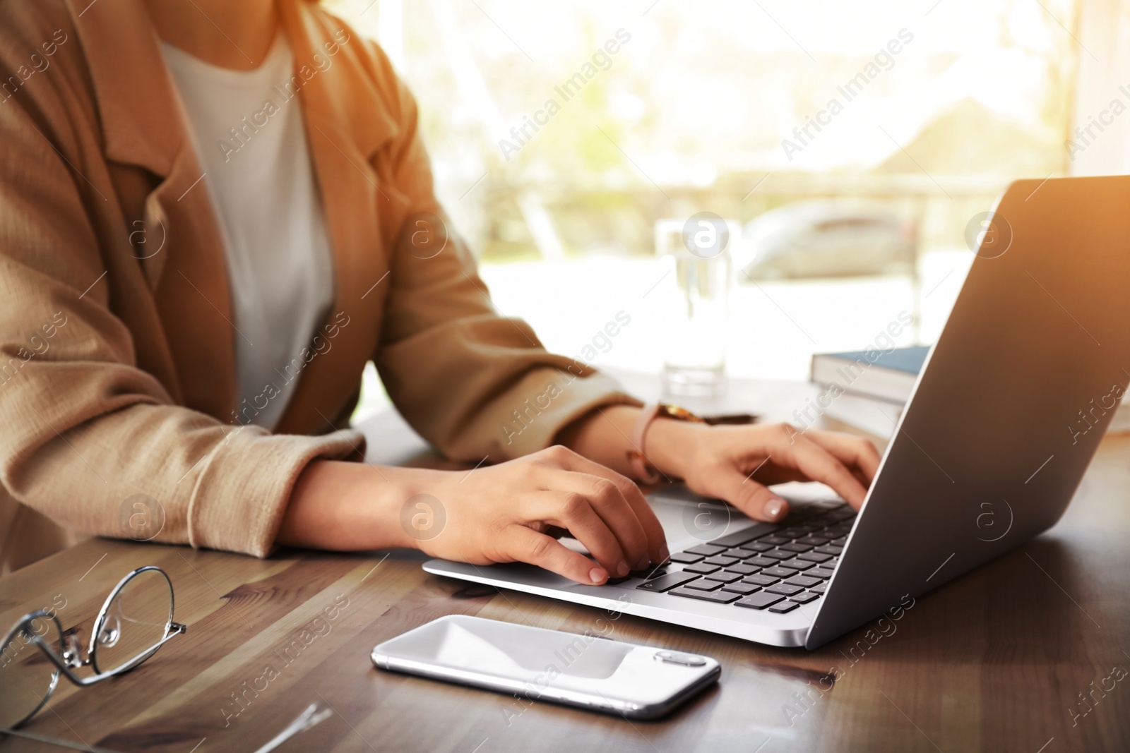 Image of Woman working with laptop at table in office, closeup