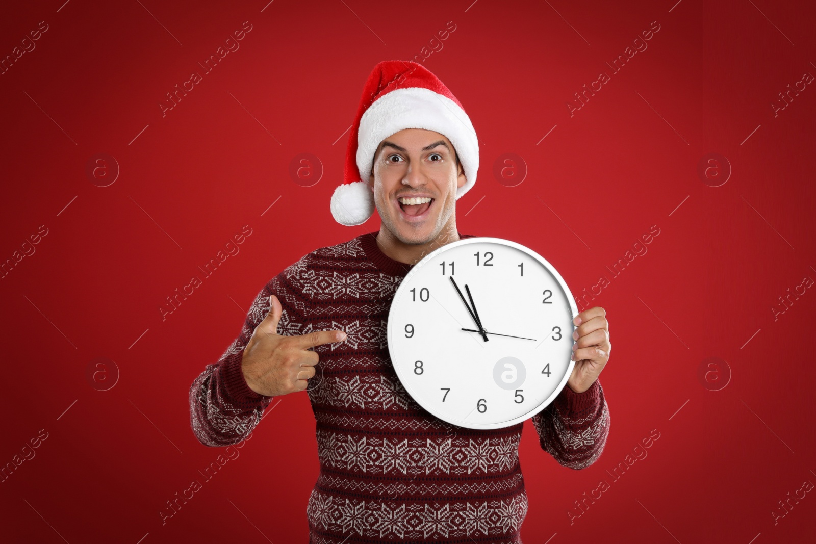 Photo of Man in Santa hat with clock on red background. New Year countdown