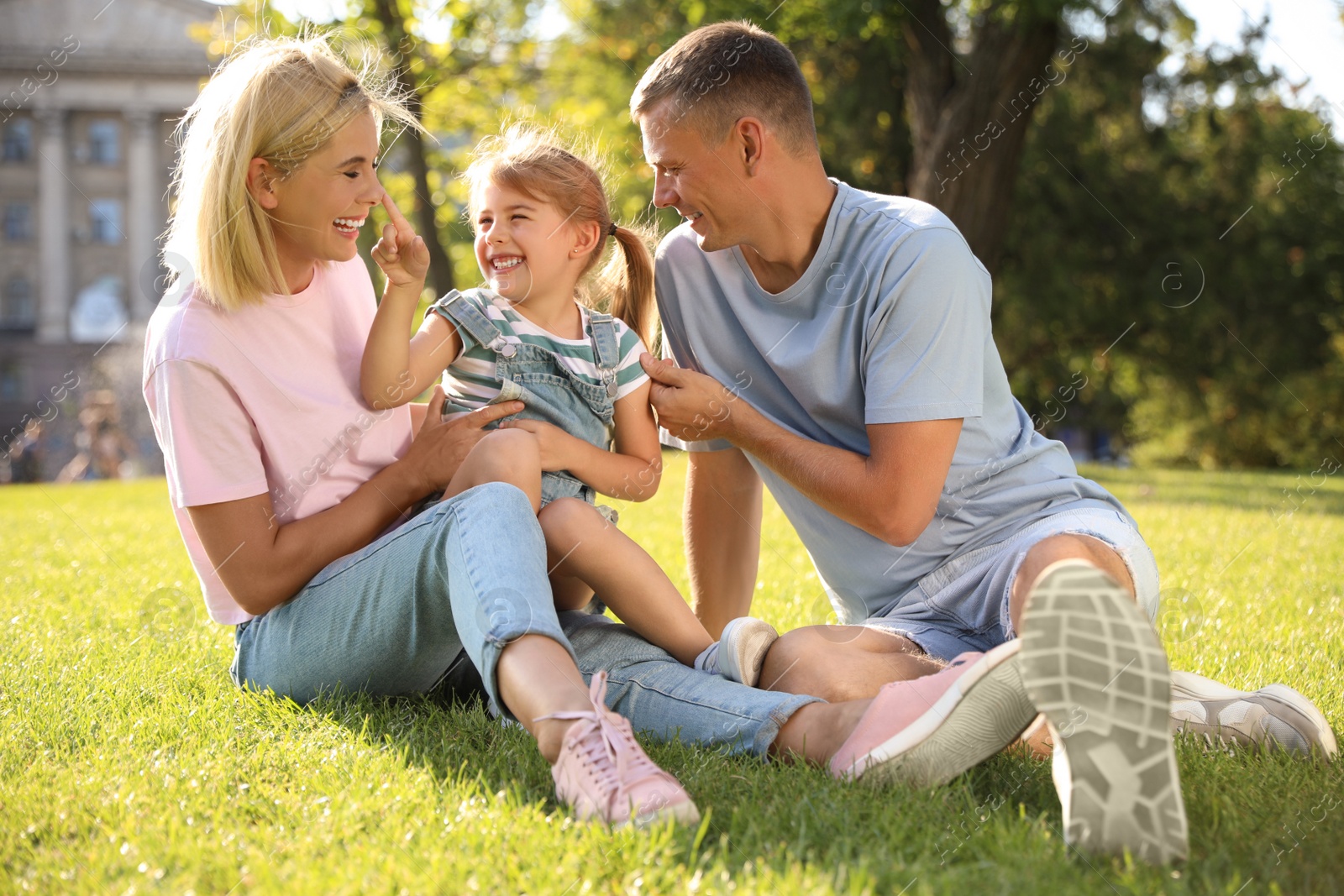 Photo of Happy parents with their child having fun on green grass. Spending time in nature