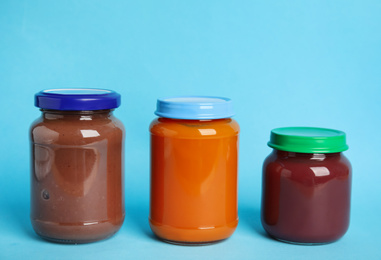 Photo of Healthy baby food in jars on light blue background