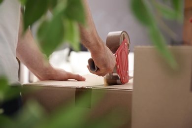 Photo of Man packing carton box indoors, closeup. Moving day