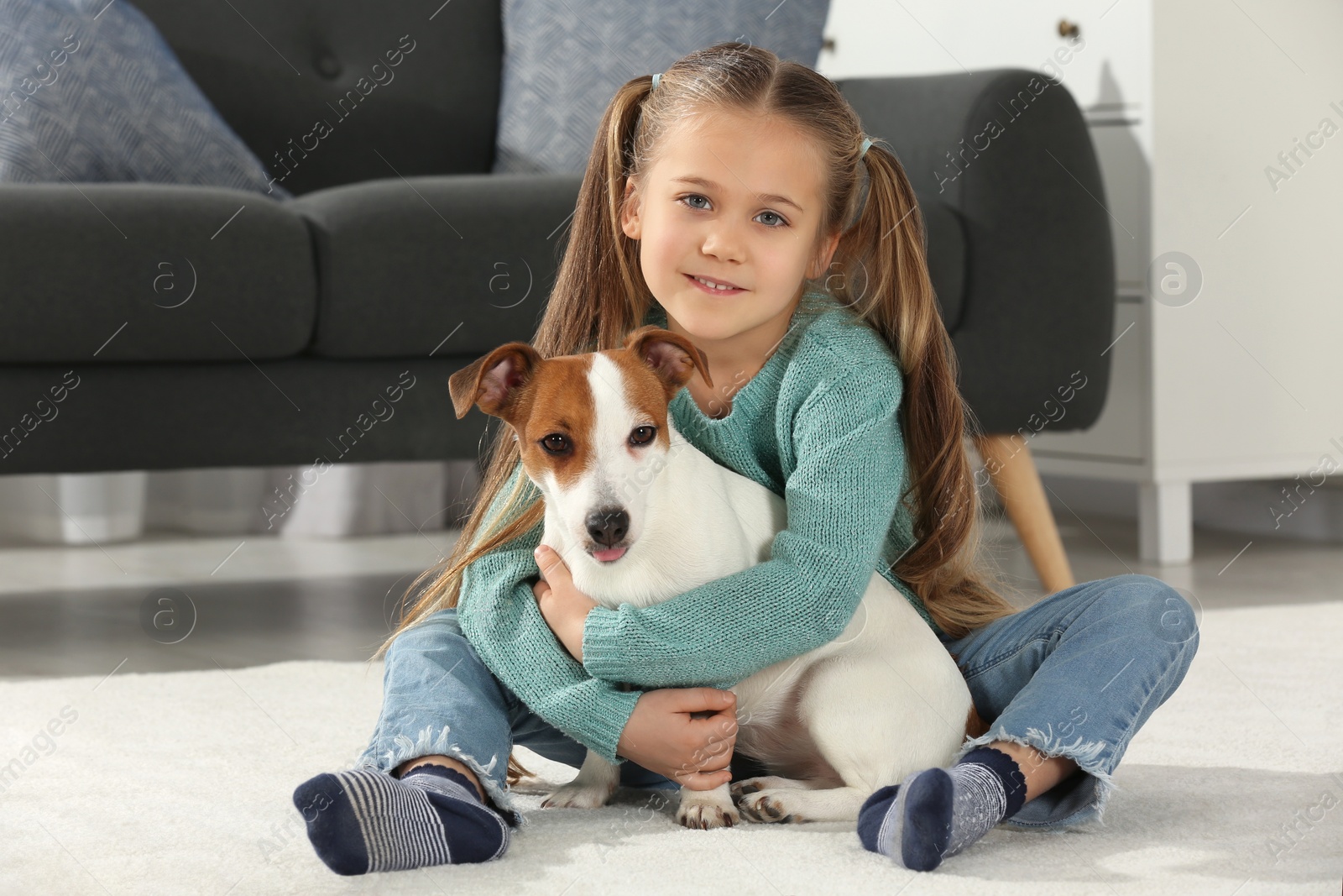 Photo of Cute girl hugging her dog on floor at home. Adorable pet