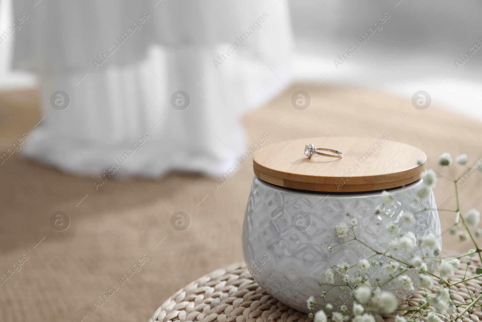 Photo of Beautiful engagement ring on jewelry jar indoors, closeup. Wedding accessory