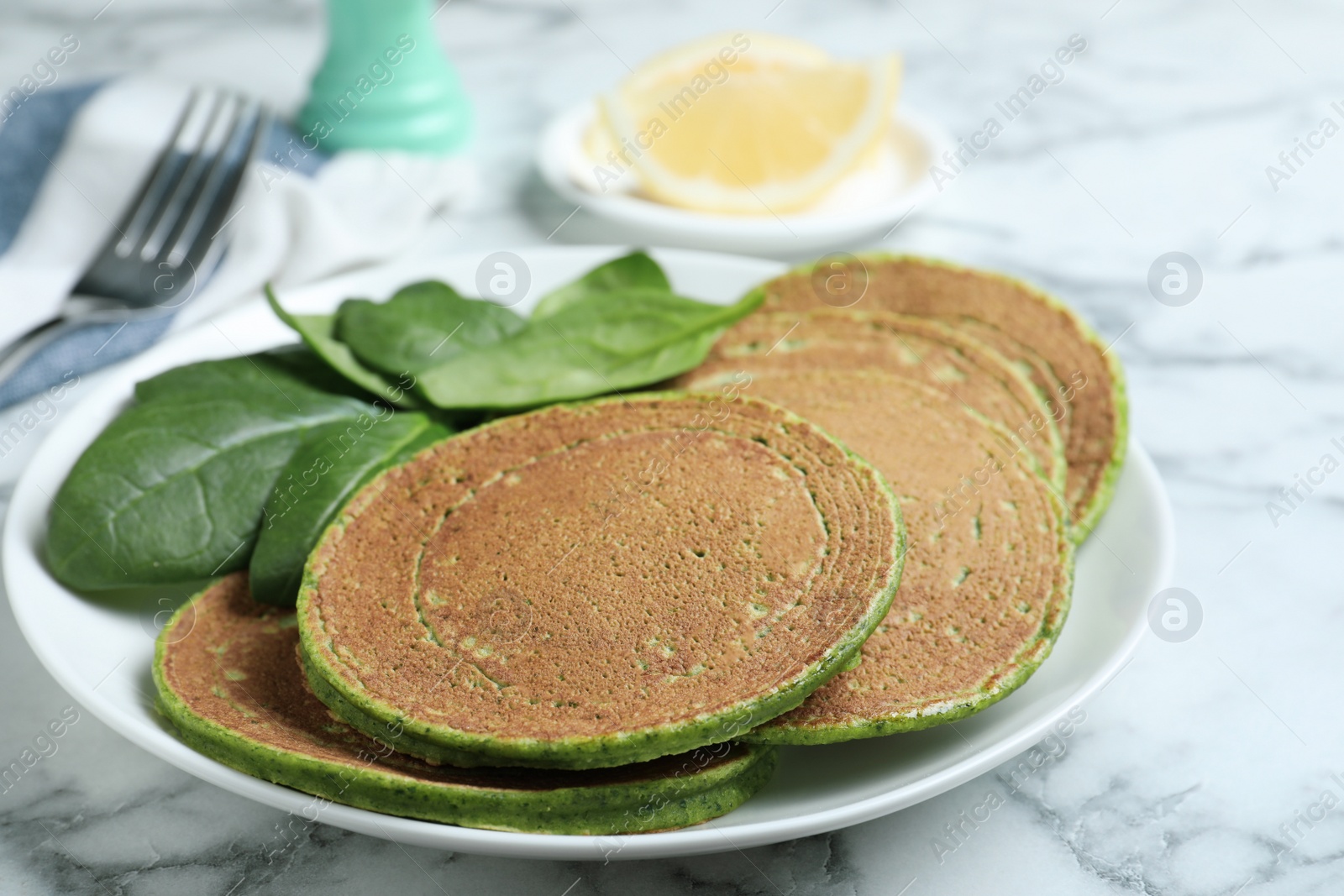 Photo of Tasty spinach pancakes on white marble table, closeup