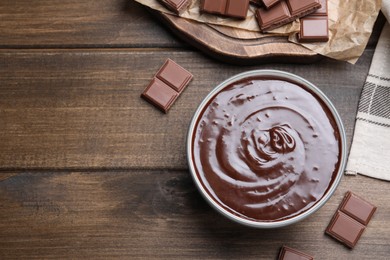 Delicious chocolate cream in bowl on wooden table, flat lay. Space for text