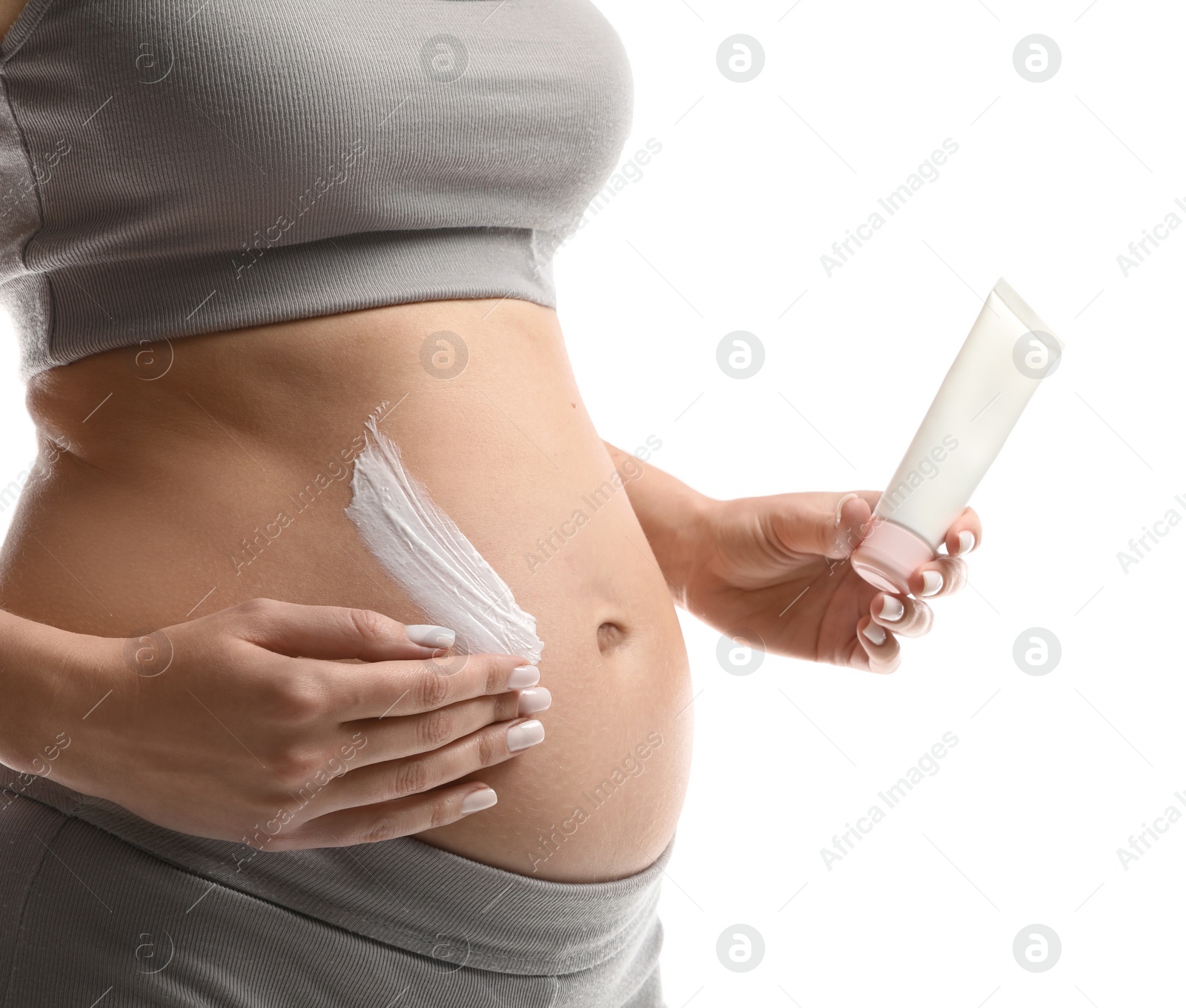 Photo of Pregnant woman applying cosmetic product on belly against white background, closeup