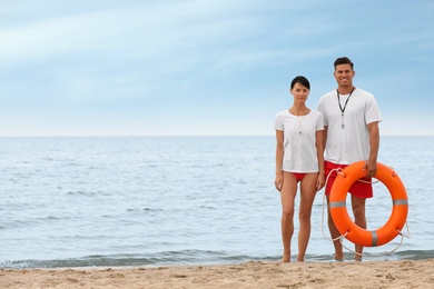 Photo of Professional lifeguards with life buoy at sandy beach