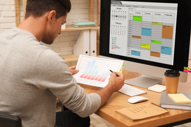 Photo of Man working with calendar at table in office
