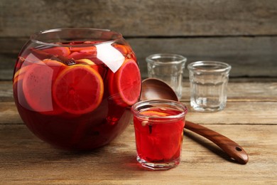 Photo of Aromatic punch drink with citrus fruits on wooden table