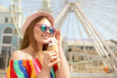 Young happy woman with ice cream cone in amusement park. Space for text