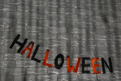 Photo of Word Halloween made of colorful letters on brick wall. Festive decor