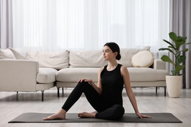 Photo of Beautiful girl sitting on yoga mat at home