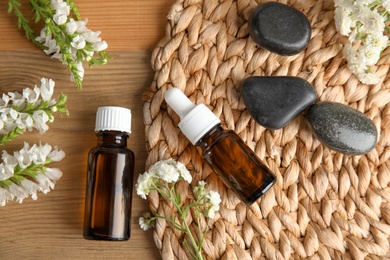 Photo of Flat lay composition with essential oil, spa stones and flowers on table