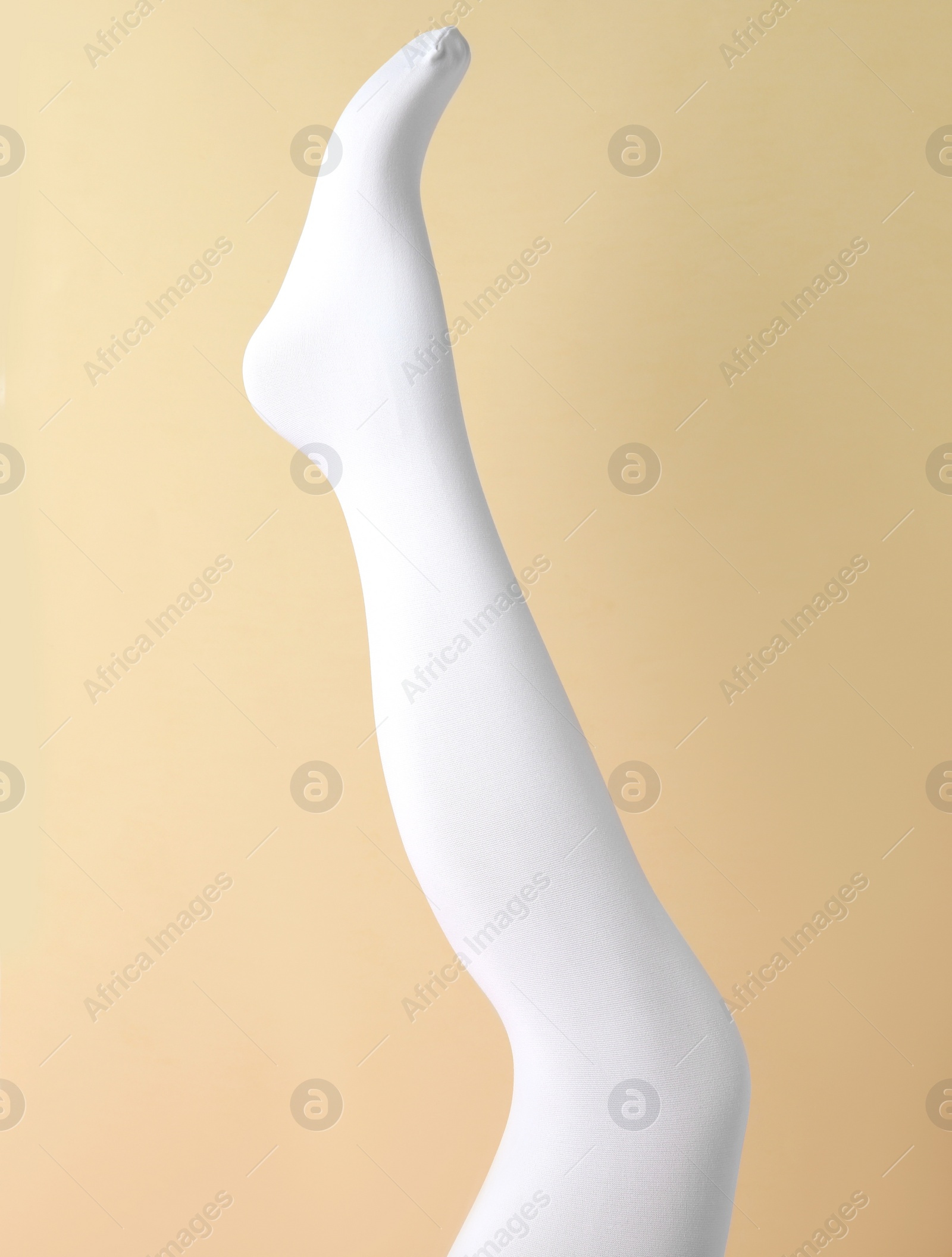 Photo of Leg mannequin in white tights on beige background