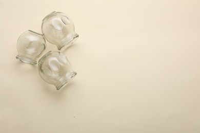 Photo of Glass cups on beige background, flat lay with space for text. Cupping therapy