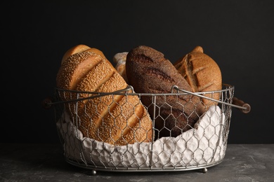 Basket with fresh bread on table against black background