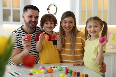 Photo of Easter celebration. Portrait of happy family with painted eggs at white marble table in kitchen