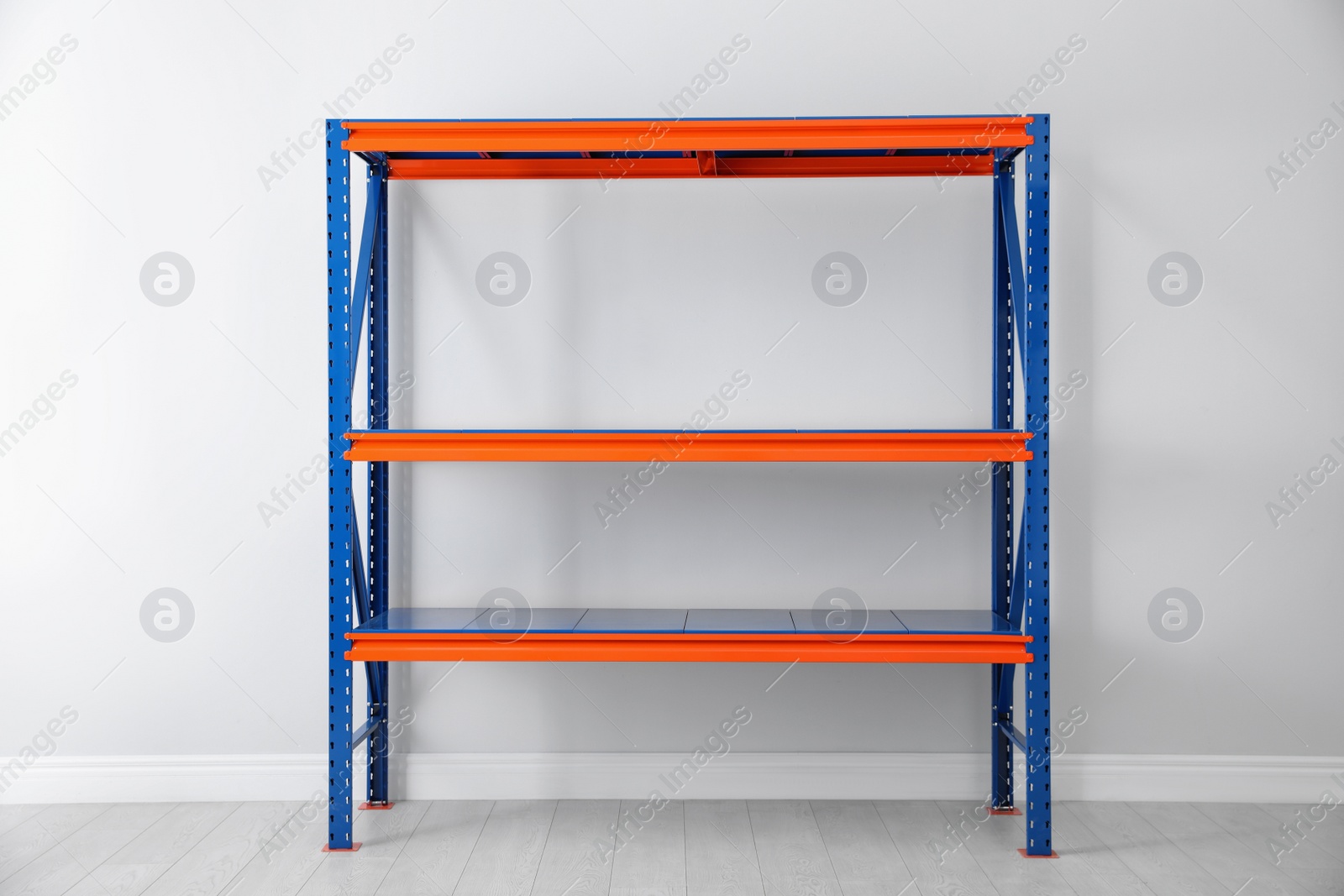 Photo of Empty metal shelving unit near light wall