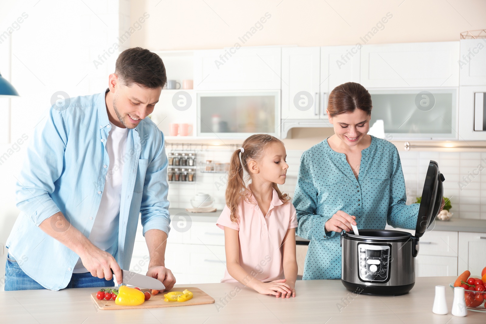 Photo of Happy family preparing food with modern multi cooker in kitchen