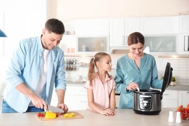 Happy family preparing food with modern multi cooker in kitchen